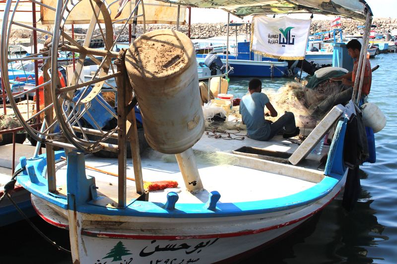 صيّادان على مركب صيد يرفع راية تاليا، أحد المشاريع التي دعمتها الجمعية.